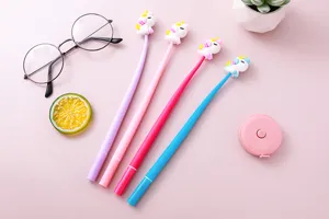 Detailed view of four colorful unicorn gel pens with soft cartoon toppers on pink desk