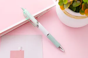 Dettaglio di una penna gel a scatto verde menta con impugnatura su sfondo rosa pastello