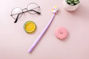 Top view of a cute purple unicorn gel pen set on a pink desk with creative props.