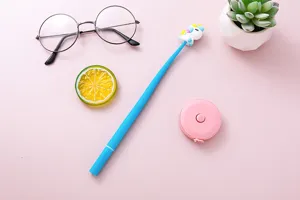 Flat lay of a cute unicorn shaking gel pen with glasses and props on pink surface
