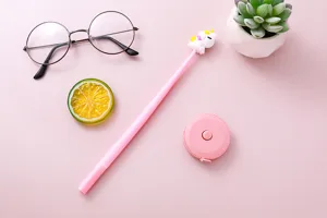 Macro view of cute pink unicorn gel pen and round measuring tape on a pink background