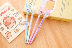 Set di quattro penne gel a forma di coniglio con paillettes liquide su scrivania in legno