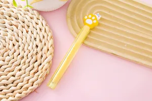 Dettaglio di una simpatica penna gel gialla con tappo a zampa di gatto su sfondo rosa