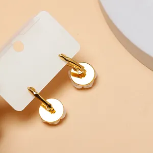 Gold leverback earrings with white flower pendants on display card, elegant versatile accessory.