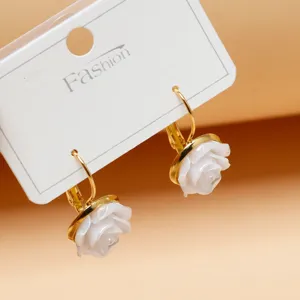 Detailed close-up of white flower earrings on a white card, elegant jewelry detail shot.