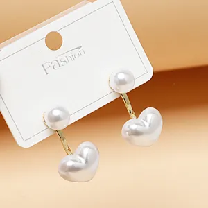 Close-up detail of trendy double pearl heart drop earrings, elegant sweet style jewelry.