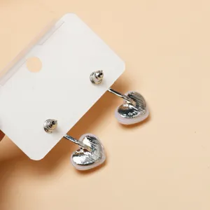 Close-up detail shot of silver heart-shaped earrings on display card, clean jewelry photography.
