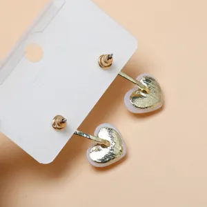 Close-up detail of stylish gold heart-shaped earrings on display card, elegant jewelry accessory.