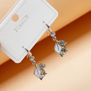 Close-up view of elegant rhinestone leaf and crystal pendant hook earrings on display card.
