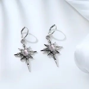 Detailed close-up shot of silver-tone multi-pointed star earrings featuring a pink crystal center.