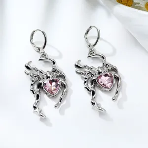 Close-up detail view of the silver-tone spider earrings featuring pink heart crystal stones.