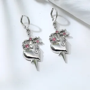 Detailed shot of silver-tone heart and dagger drop earrings adorned with sparkling pink rhinestones.