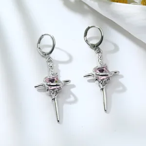 Detailed close-up shot of the silver cross pendant earrings featuring a sparkling pink gem.