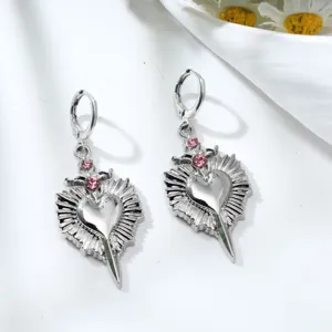 Detailed shot of silver alloy heart and dagger earrings adorned with sparkling pink rhinestones.