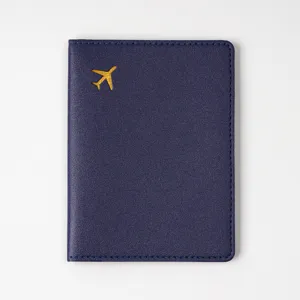 Detailed view of the navy blue passport cover featuring a stylish gold airplane logo.