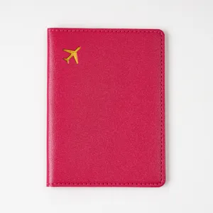Detailed view of a rose red thick PVC leather passport cover featuring a golden airplane.