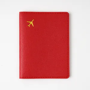 Red leather passport cover with gold airplane motif, travel document holder organizer.