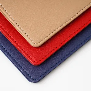 Close-up detail shot of multi-color PVC leather passport cover with neat white edge stitching.