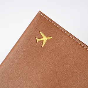 Brown passport cover detail view, featuring gold airplane logo and neat white edge stitching.