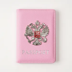 Detail view of the pink PU leather passport cover featuring a metallic double-headed eagle emblem.