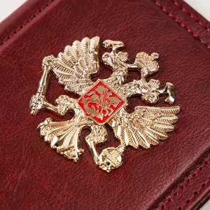 Red vintage leather passport cover featuring a detailed golden double eagle metal badge.