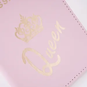 Pink PU leather passport holder detail shot featuring gold foil crown and Queen text embossing.