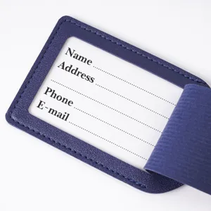 Close-up detail view of dark blue leather luggage tag featuring clear card window slot.