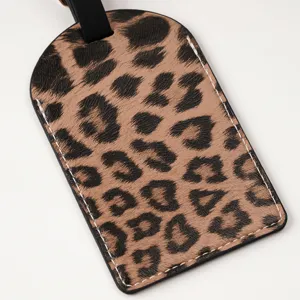 Detailaufnahme eines modischen Kofferanhängers aus PU-Leder mit Leopardenmuster und Riemen.
