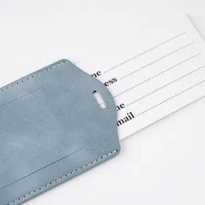 Primer plano de etiqueta de equipaje de cuero azul claro con tarjeta de dirección blanca.