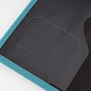 Detail view of passport cover with turquoise blue stitching and transparent card slot pocket.
