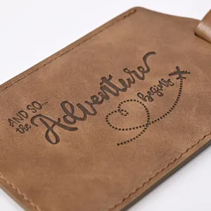 Brown PU leather luggage tag with embossed adventure quote, durable travel suitcase accessory.