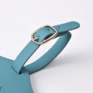 Close-up of teal PU leather luggage tag strap with a polished gold-toned metal buckle detail.