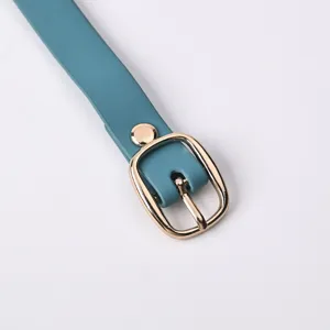 Detailed close-up showing the cyan luggage tag strap with a golden metal buckle and rivet.