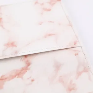 Detail shot of pink marble passport holder travel document organizer with neat white stitching.