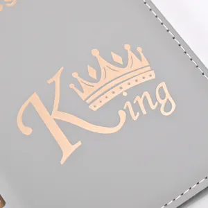 Close up view of grey PU leather passport cover with rose gold King typography and crown design.