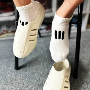 White short socks with three black stripes worn in casual foam clogs, detail view.
