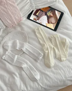 Rüschen-Netz-Wadenstrümpfe Detailaufnahme, gemütlicher Flat-Lay-Stil mit weißem Stoff und Requisiten.