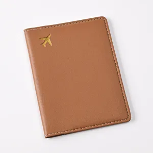 Brown PU leather passport cover with gold foil airplane pattern and white edge stitching.