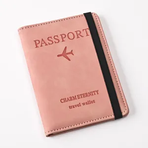 Pink PU leather passport holder detail shot, elastic band closure and embossed travel design.