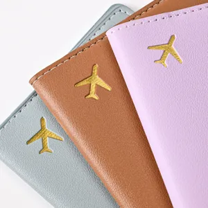 Detailed view of multi-color PU leather passport holders with gold airplane stamped designs.