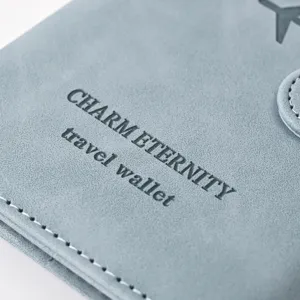 Close-up detail of grey PU leather passport wallet showing debossed letters and fine stitching.