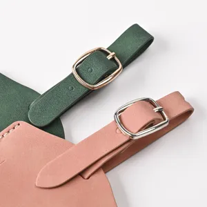 Close-up detail of green and pink PU leather luggage tags featuring metallic adjustable buckles.