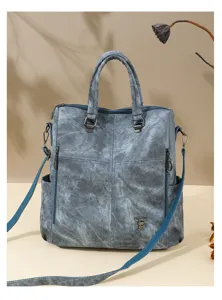 Detail view of the blue-grey soft leather convertible backpack with metal rabbit charm.
