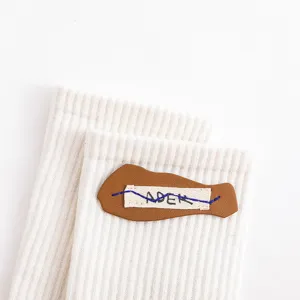Detailansicht der stylischen gerippten Socken in Beige mit einem besonderen Lederetikett.