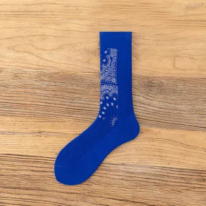 Close-up view of blue crew socks featuring a detailed white paisley pattern on the rib.