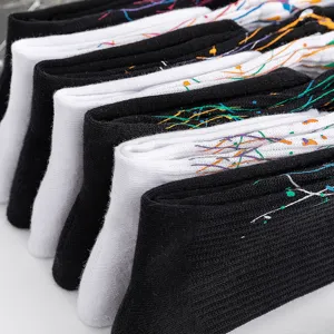 Close-up detail of stylish black and white crew socks featuring colorful paint splatter print.
