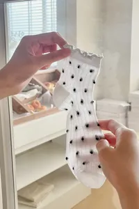 Sheer mesh ankle socks featuring black polka dots and delicate lettuce trim details.
