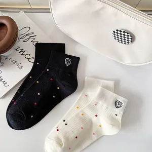 Dettaglio ravvicinato di calzini corti in cotone da donna con pois e ricamo a cuore.