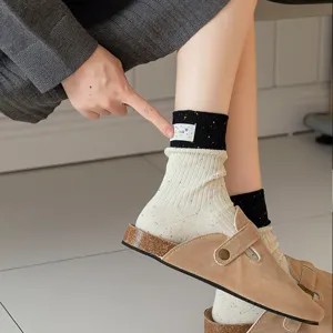 Detailaufnahme koreanischer Fleckgarn-Mittelsocken mit Bündchenetikett und Farblock-Design.