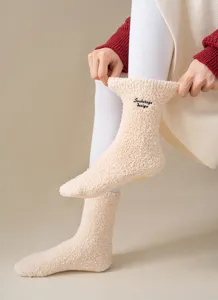 Close-up detail of fluffy fleece warm slouch socks with cute embroidered letter design.